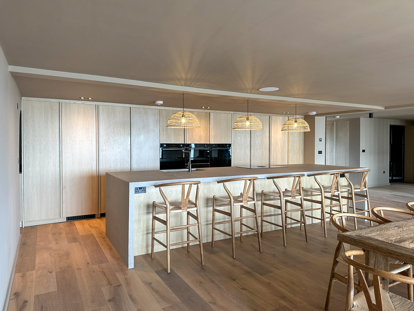 Modern kitchen with island and bar stools in a well-lit room.