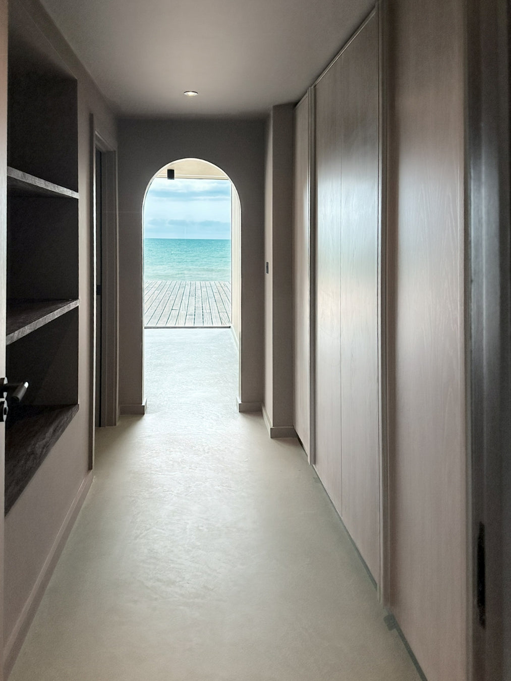 Modern interior with a hallway leading to a door with a view of the sea