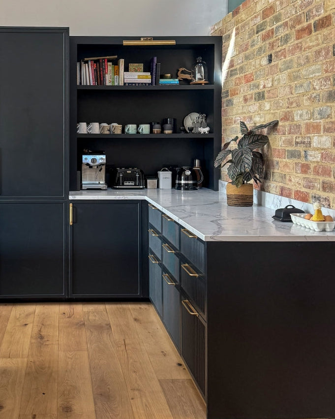Modern kitchen with shaker kitchen cabinets, open shelf, and brick wall.