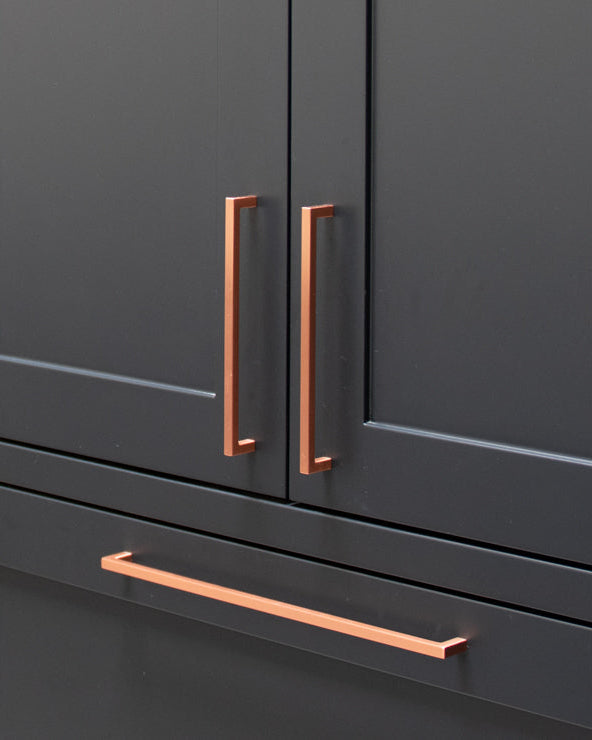 Dark gray kitchen cabinets with copper handles in a modern kitchen setting.