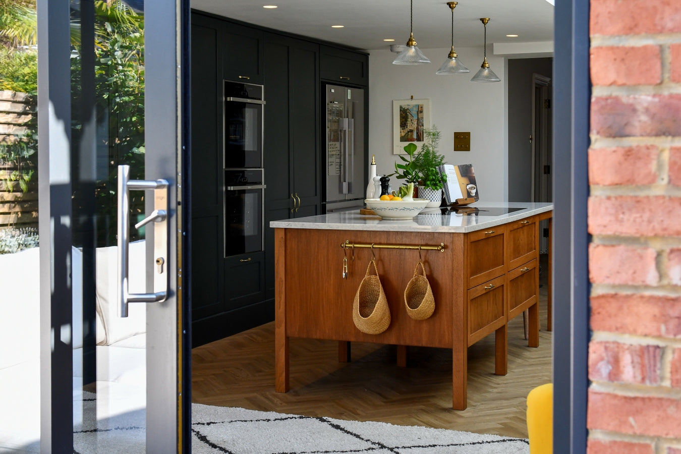 Modern kitchen with stained oak island andstudio greencabinets, viewed through a frenchdoor,
