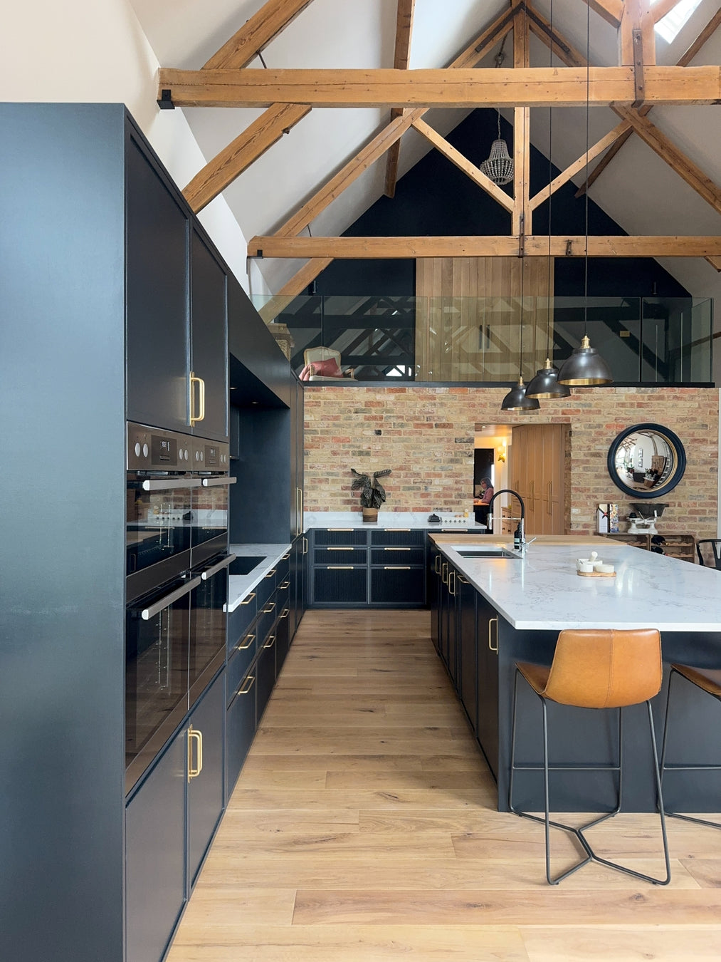 Modern kitchen with dark blue cabinets, wooden floor, and island with bar stool.