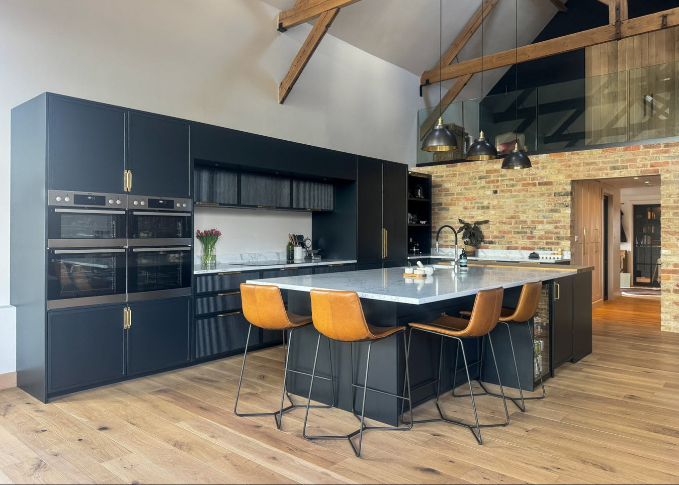 Shaker limline kitchen with reeded cabinets, a island, and orange stools.