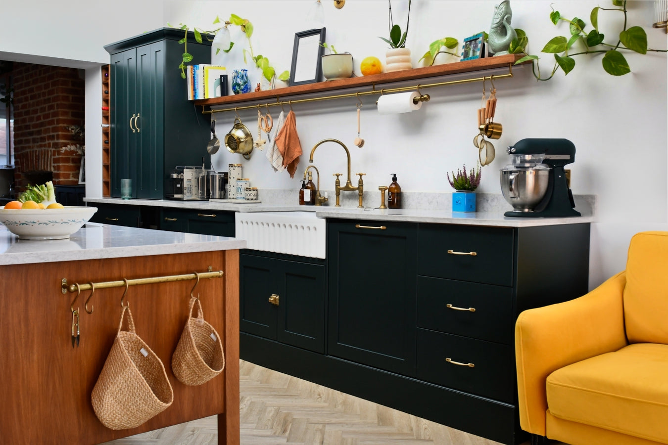 Modern kitchen with studio green cabinets, white worktop, and a yellow chair.
