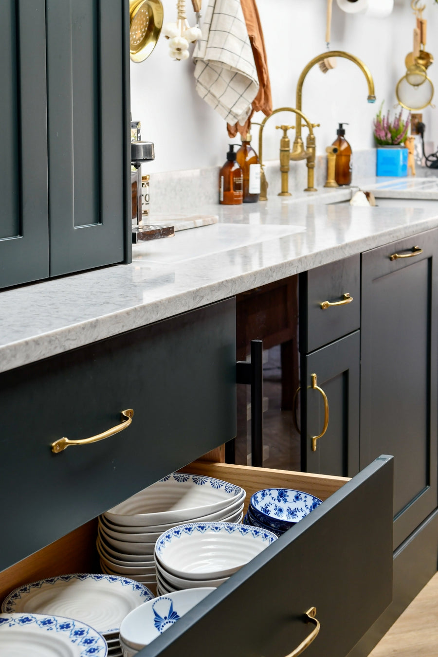 Kitchen with open drawer displaying plates, granite countertop, and brass tap